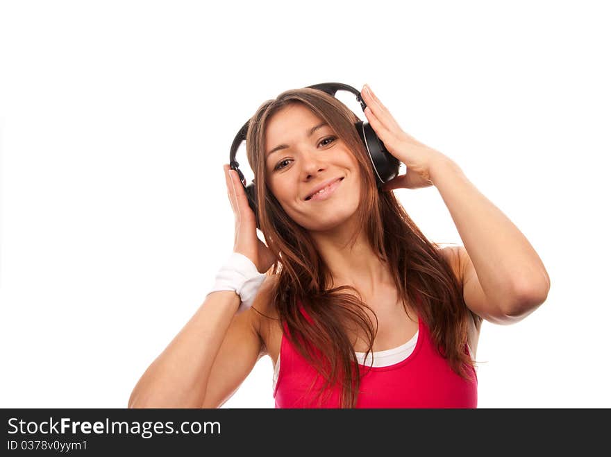 Attractive fitness brunette woman listening and enjoyingmusic in headphones, smiling, laughing and looking in camera isolated on a white background