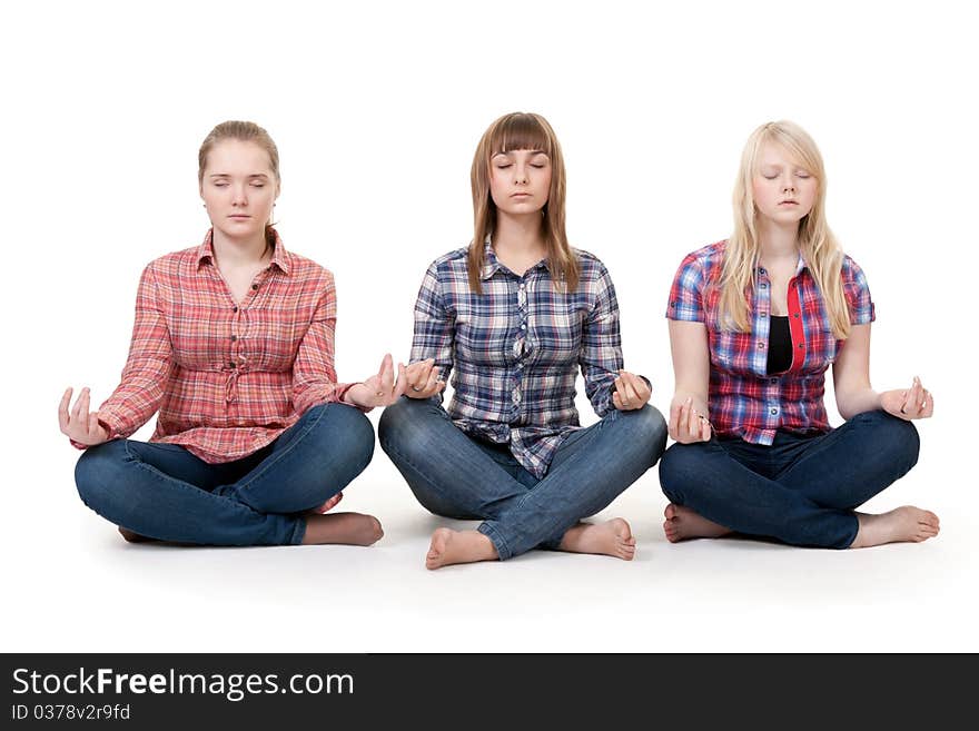 Three girls sitting in lotus posture on a white background