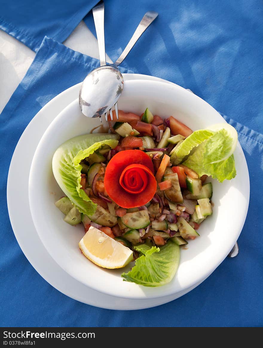 Dish with a salad in a restaurant with blue napkins