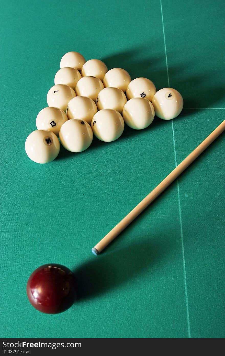 Billiards table with balls and a cue stick