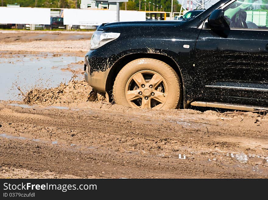 A car sprays mud as it zips around a corner in a dirt road rally. A car sprays mud as it zips around a corner in a dirt road rally