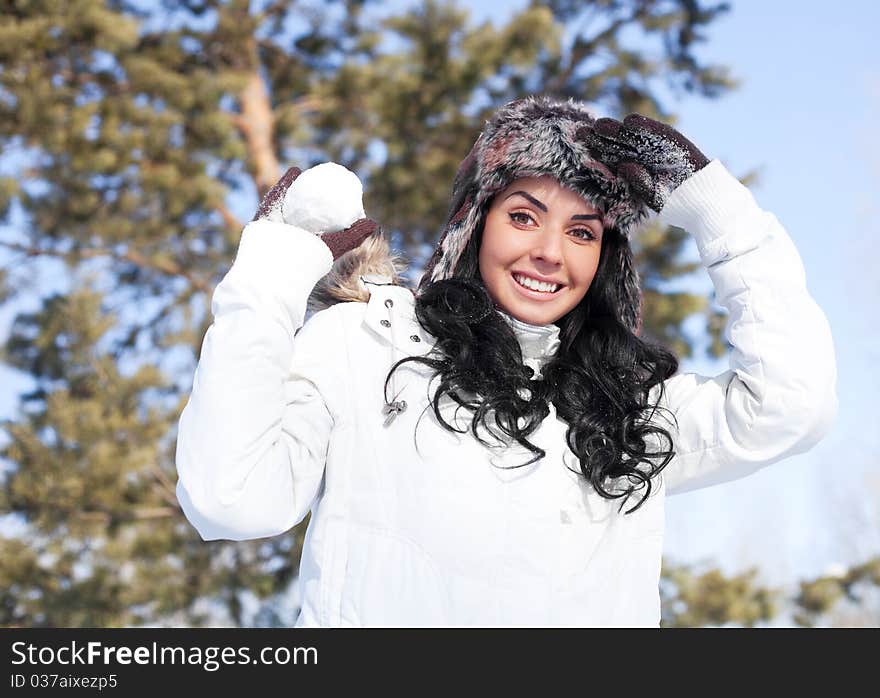 Pretty young brunette woman playing snowballs in winter outdoor. Pretty young brunette woman playing snowballs in winter outdoor