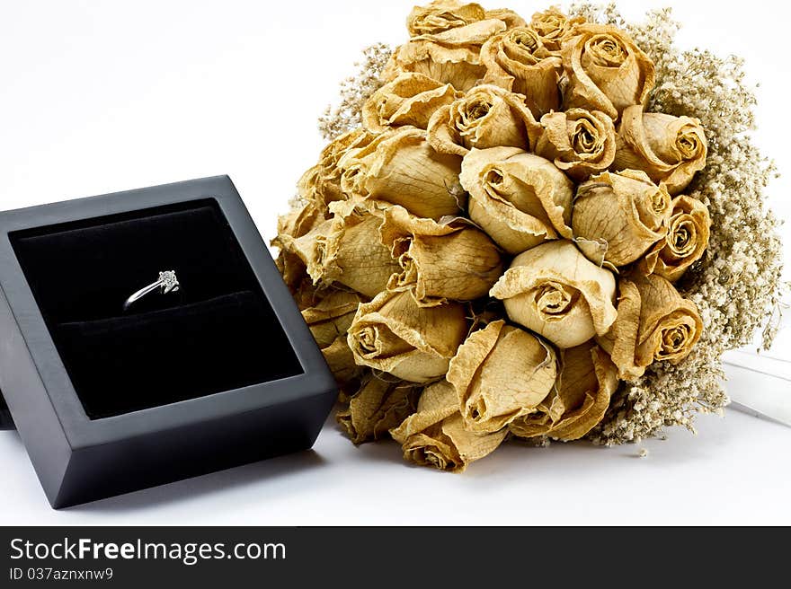 Dried roses bouquet and engagement ring on white