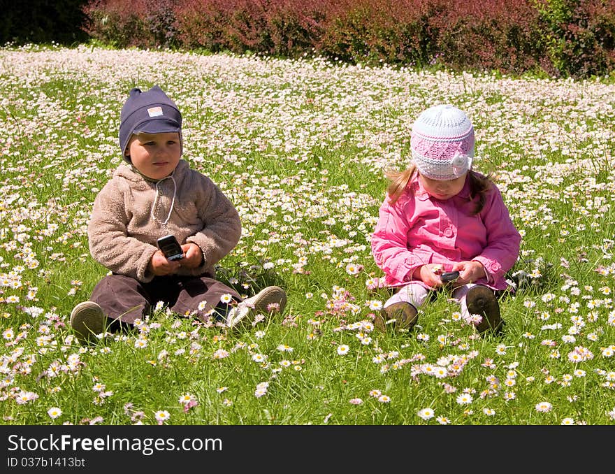 Boy and girl playing in the park with mobile phones