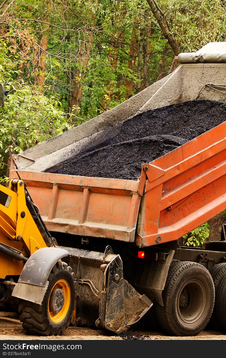 Process of unloading of asphalt of the lorry in a ladle of the building mechanism. Process of unloading of asphalt of the lorry in a ladle of the building mechanism