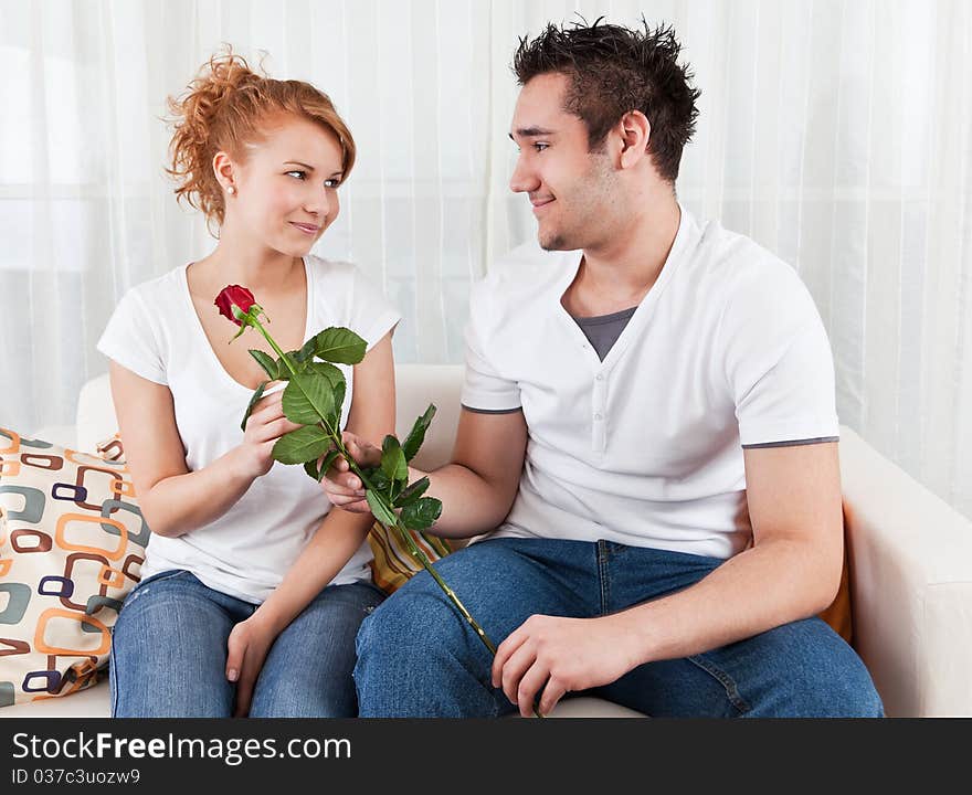 Young boy giving red rose to a beauty, young girl