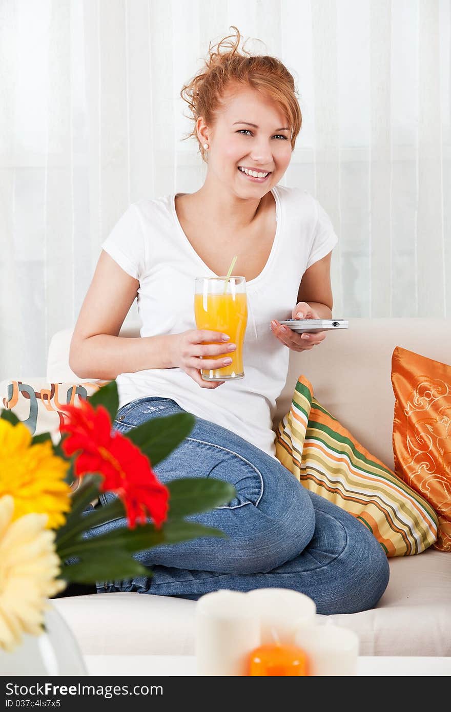 Beauty, young girl holding a glass of orange juice and a remote control. Beauty, young girl holding a glass of orange juice and a remote control