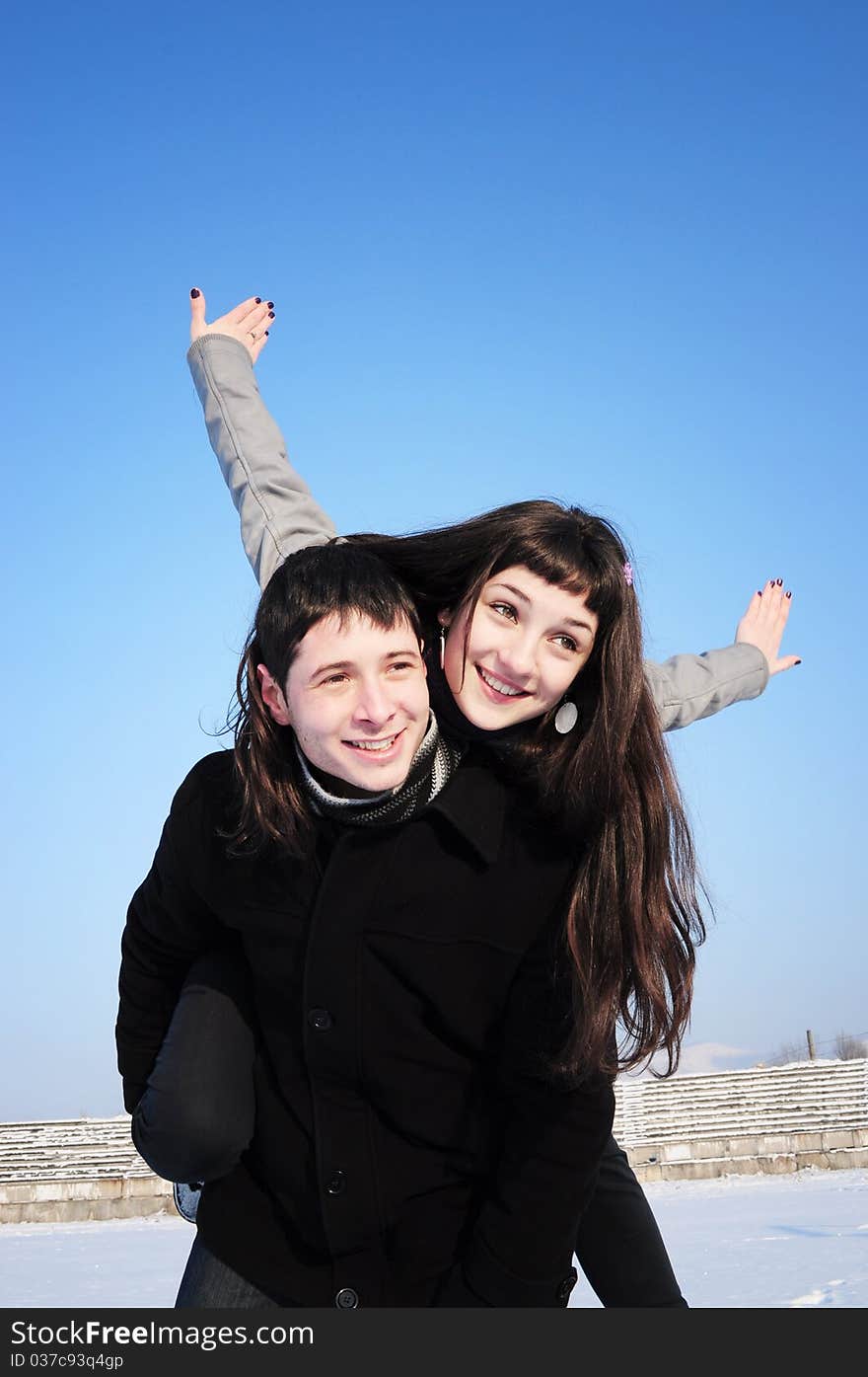 Happy young female enjoying a piggyback ride on boyfriends back with her hands outstretched. Happy young female enjoying a piggyback ride on boyfriends back with her hands outstretched