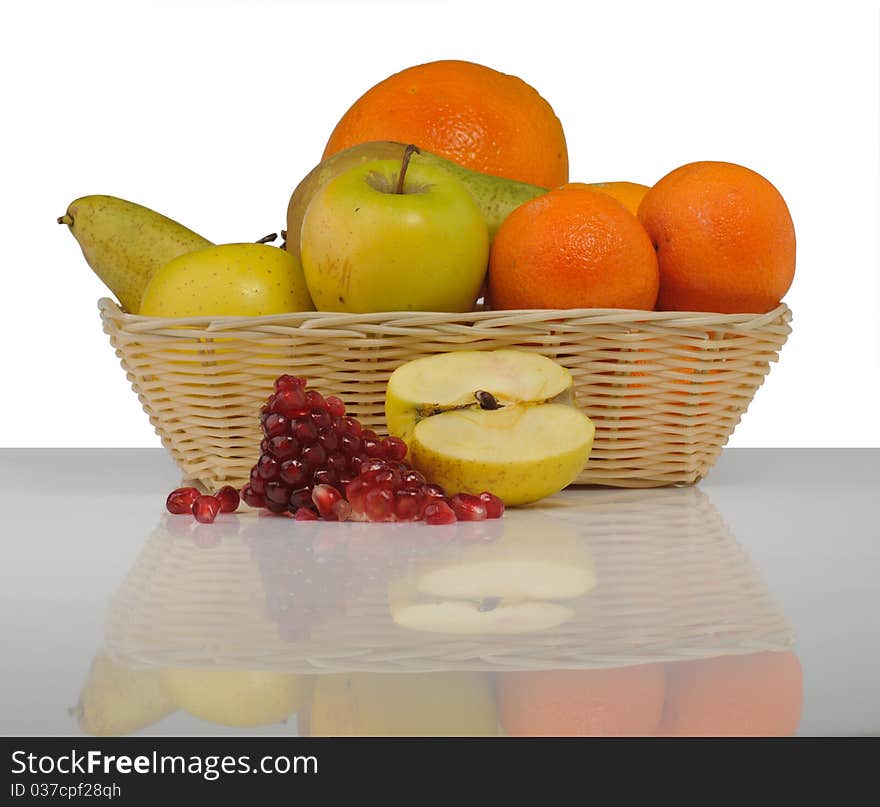 Fruit in a basket on the reflecting surface isolated on white background. Fruit in a basket on the reflecting surface isolated on white background