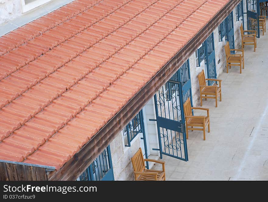 Courtyard with blue doors and wood chairs under red tile roof. Courtyard with blue doors and wood chairs under red tile roof