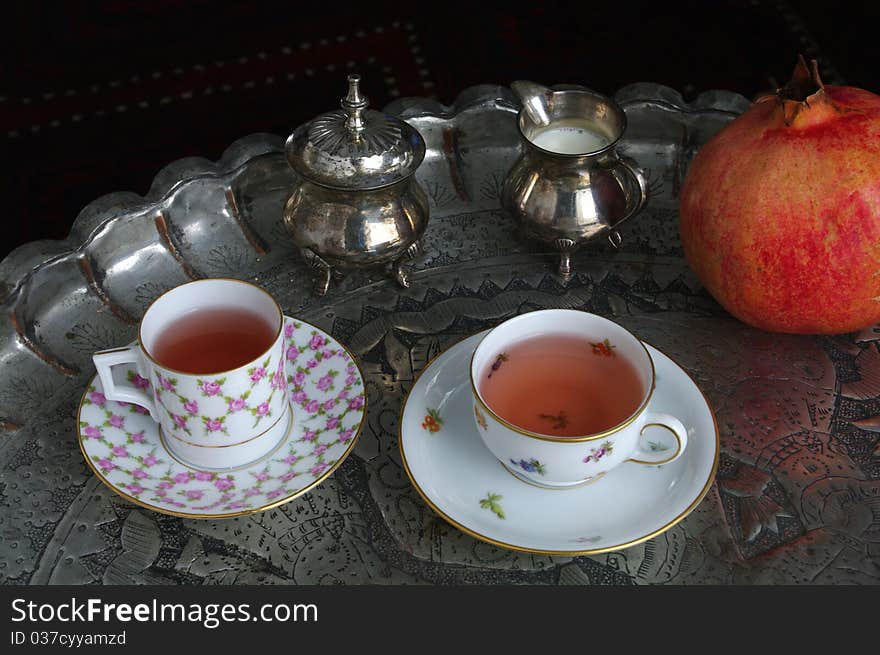 Oriental Tea Time Still Life with China Cups, Silverware and Grenadine Fruit Decoration