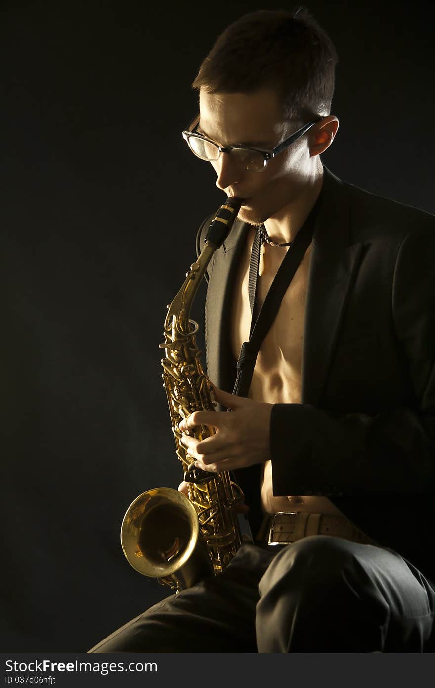 Young jazzman plaing a saxophone on black