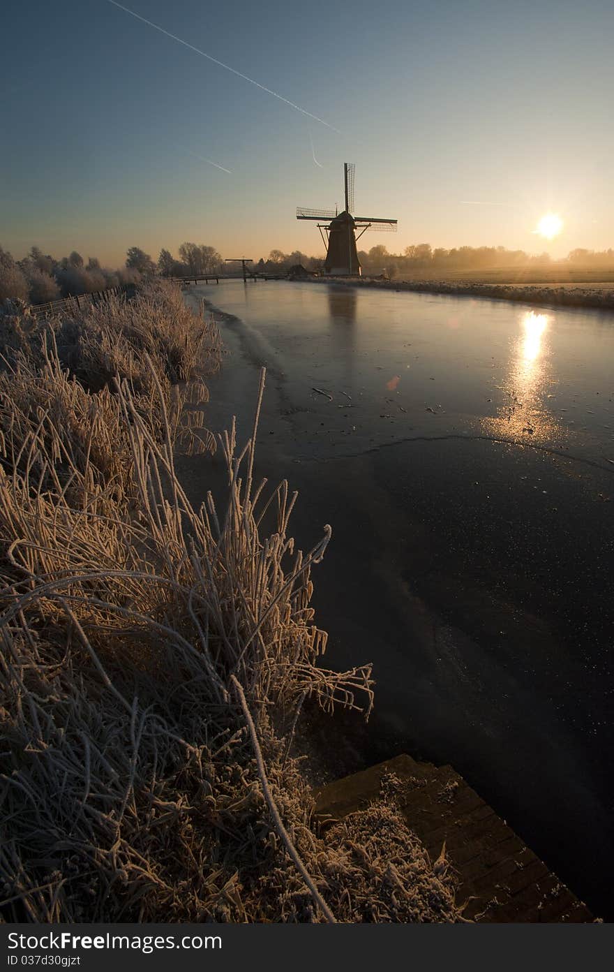 Dutch landscape of a frozen river with an old windmill in the background. Dutch landscape of a frozen river with an old windmill in the background.