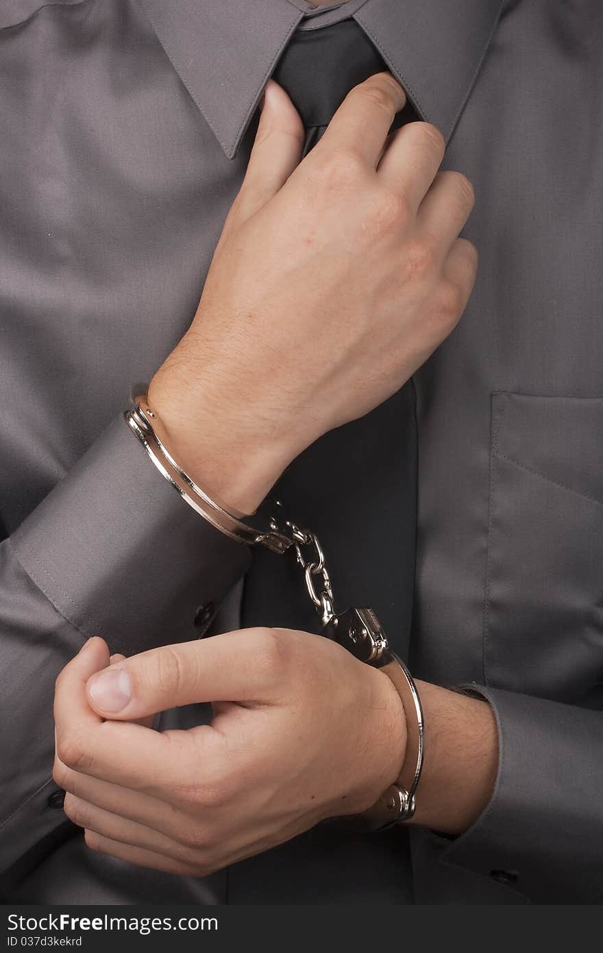 Arrested white man in handcuffs straightens his tie.