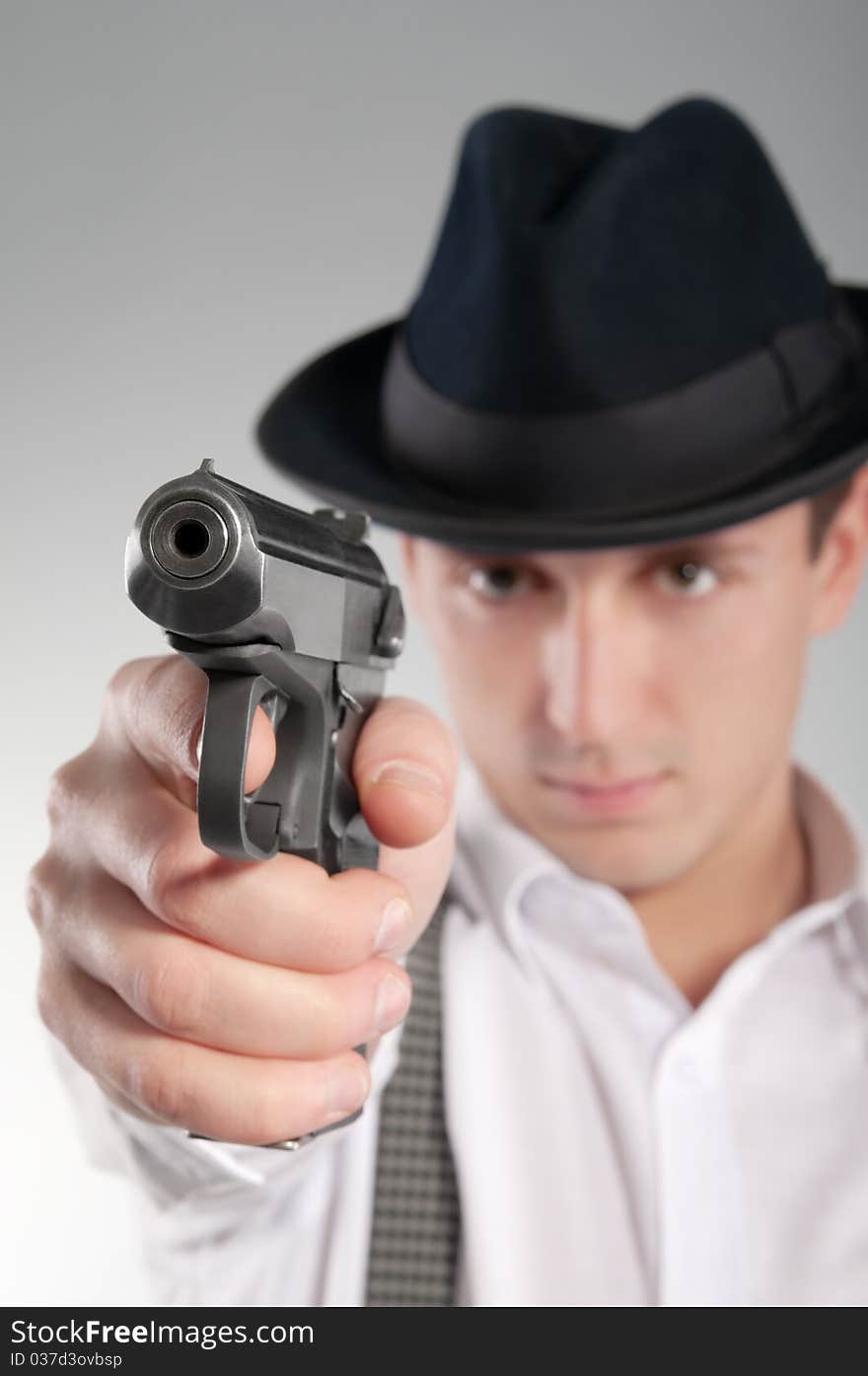 Dangerous gangster in hat aims a pistol