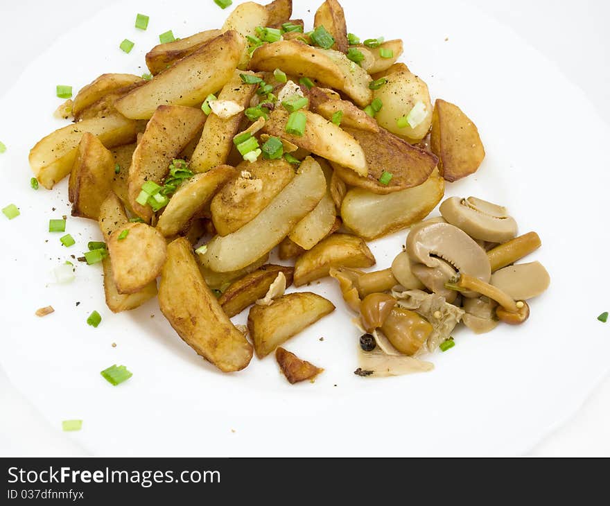 Fried potatoes with pickled mushroom on white plate and is sprinkled by verdure and spice