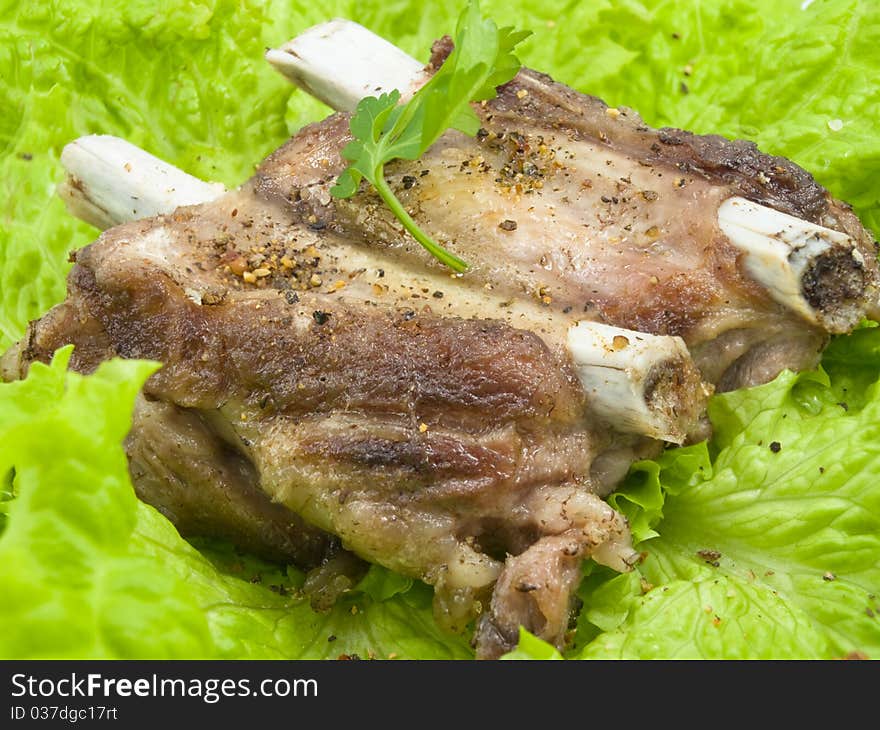 Well-done pork edges are located on leaves of salad and decorated by parsley greens. Well-done pork edges are located on leaves of salad and decorated by parsley greens