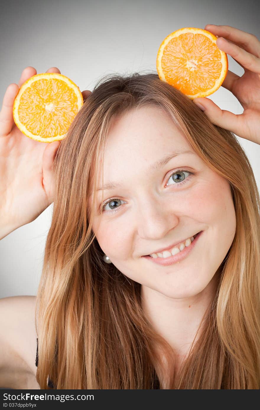 Beautiful woman holding two halfs of orange on her head like Mickey Mouse ears. Beautiful woman holding two halfs of orange on her head like Mickey Mouse ears