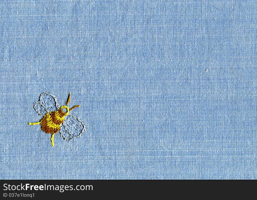 Embroidery of bee on blue cotton fabric