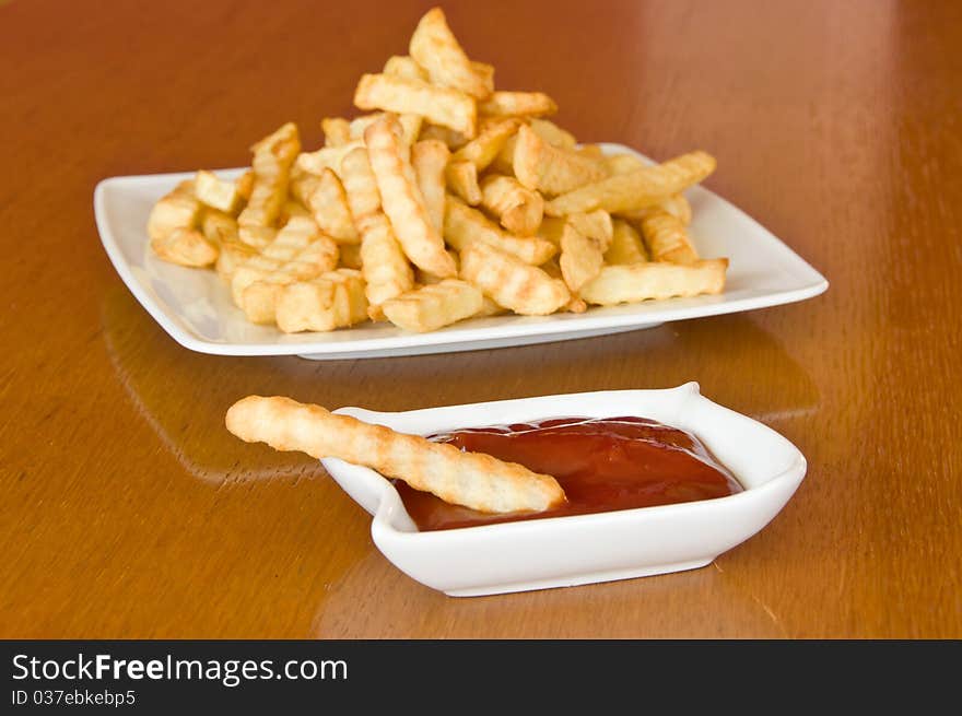 Single french fry with ketchup and  plate of fries