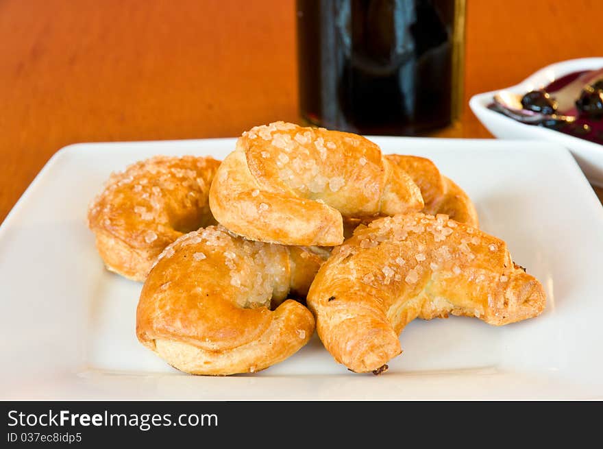 White plate of freshly baked, golden croissonts with blackberry jelly in the background. White plate of freshly baked, golden croissonts with blackberry jelly in the background