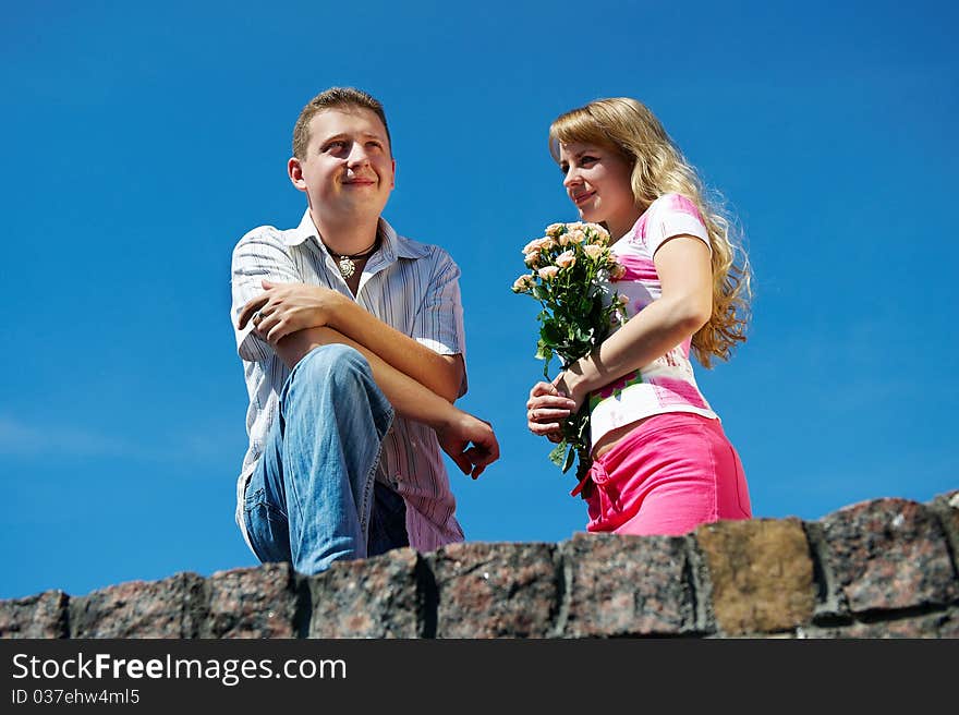 Young woman with flowers and her boyfriend on background blue sky