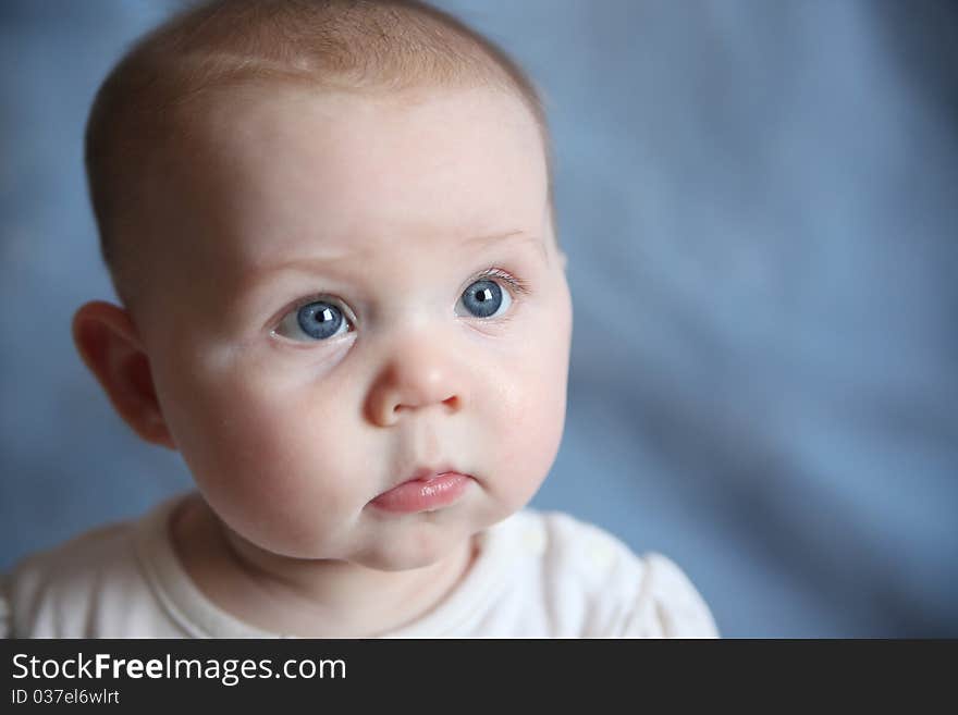 Portrait of adorable baby with big blue eyes on a blue background. Portrait of adorable baby with big blue eyes on a blue background