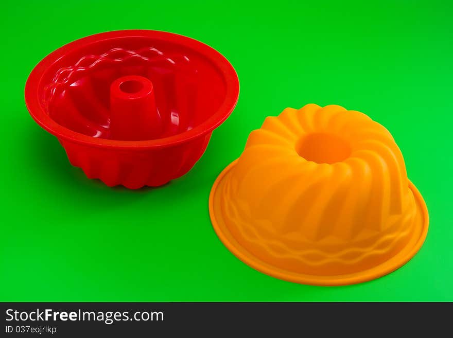 Red and orange silicone cupcake mold on green. Red and orange silicone cupcake mold on green