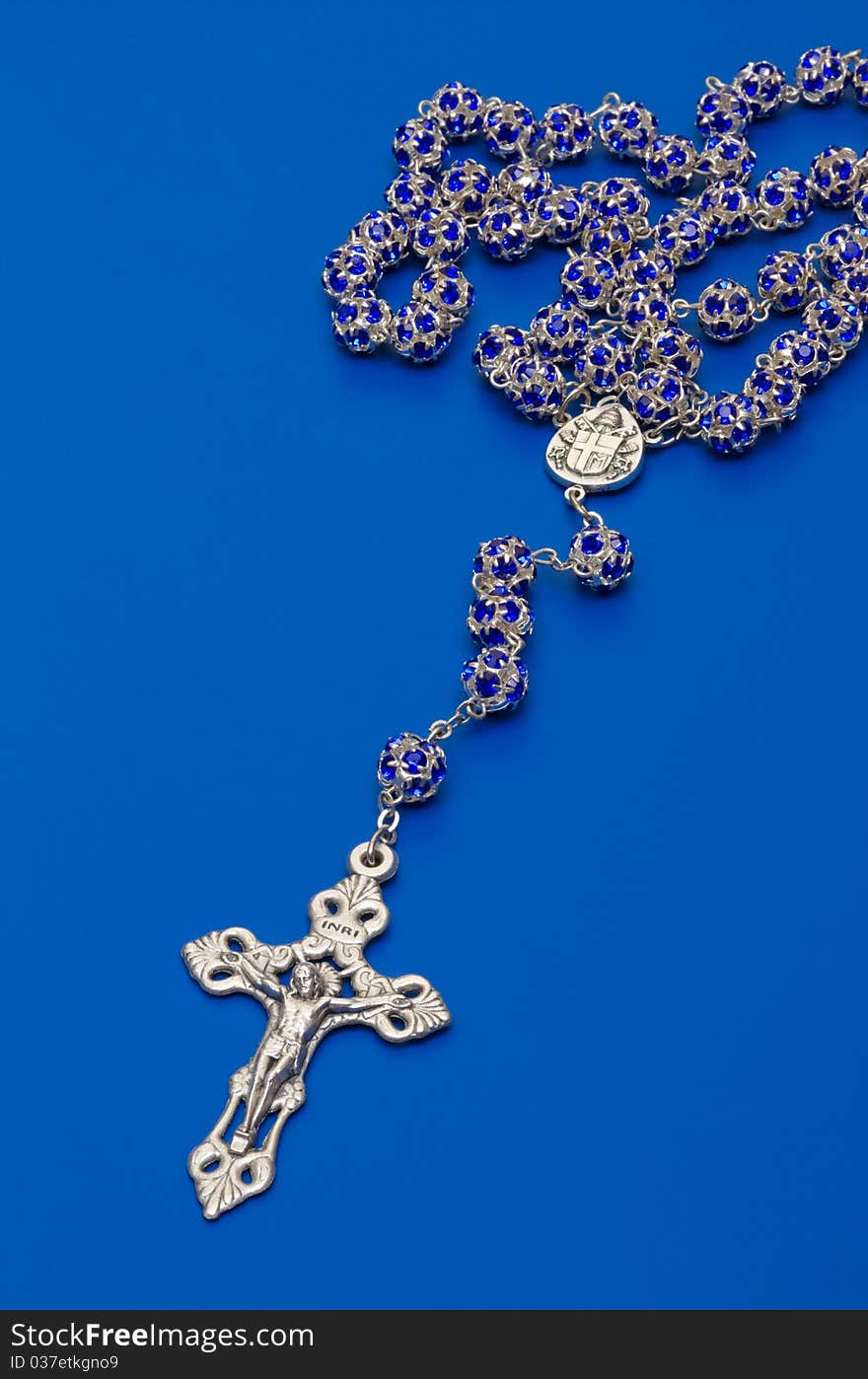 Rosary beads from glass with  salver cross on blue background