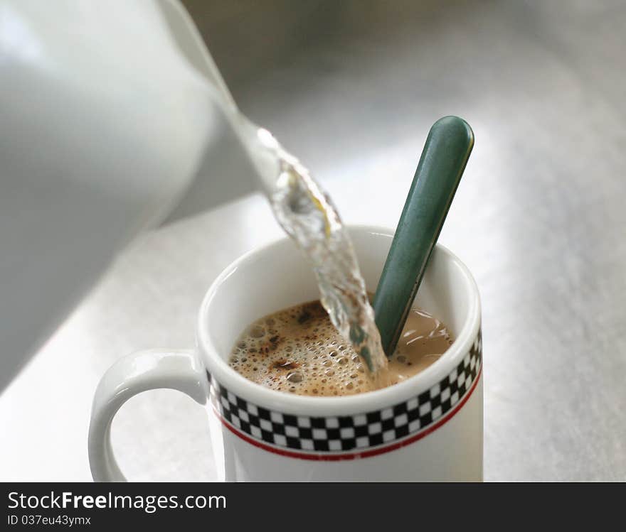 Pouring water into the morning cup of coffee. Pouring water into the morning cup of coffee