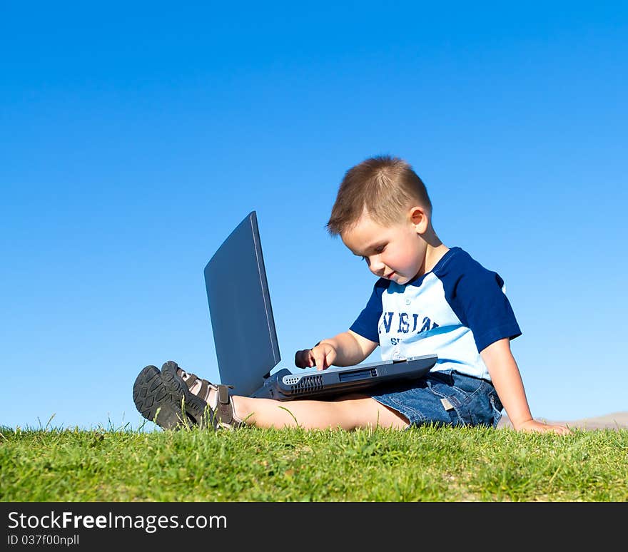 Little boy sitting down and playing with laptop. Little boy sitting down and playing with laptop