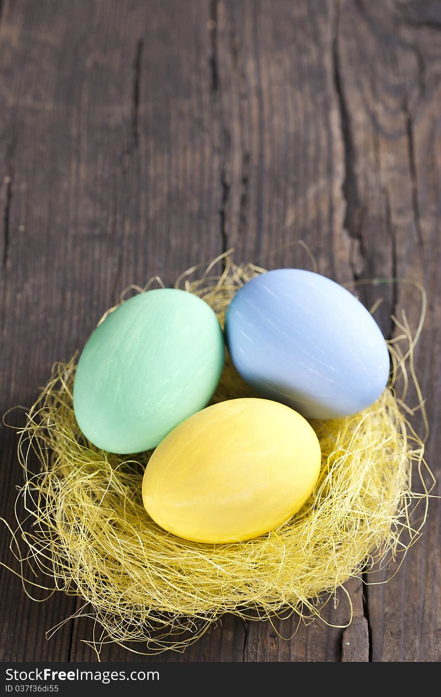 Colorful easter eggs in nest on wooden background