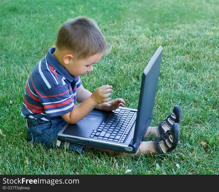 Little boy sitting down and playing with laptop. Little boy sitting down and playing with laptop