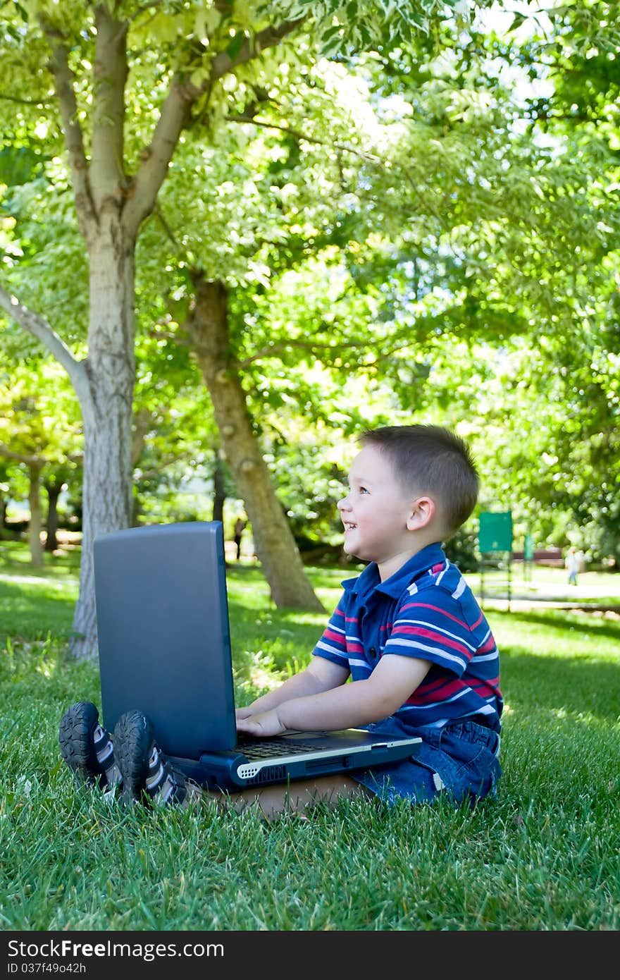 Little boy smiling while playing with laptop. Little boy smiling while playing with laptop