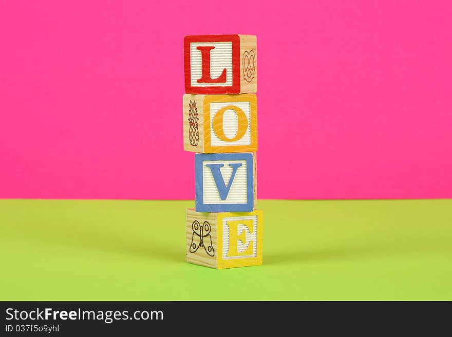 The word love spelled in childrens block with a pink and green background. The word love spelled in childrens block with a pink and green background.