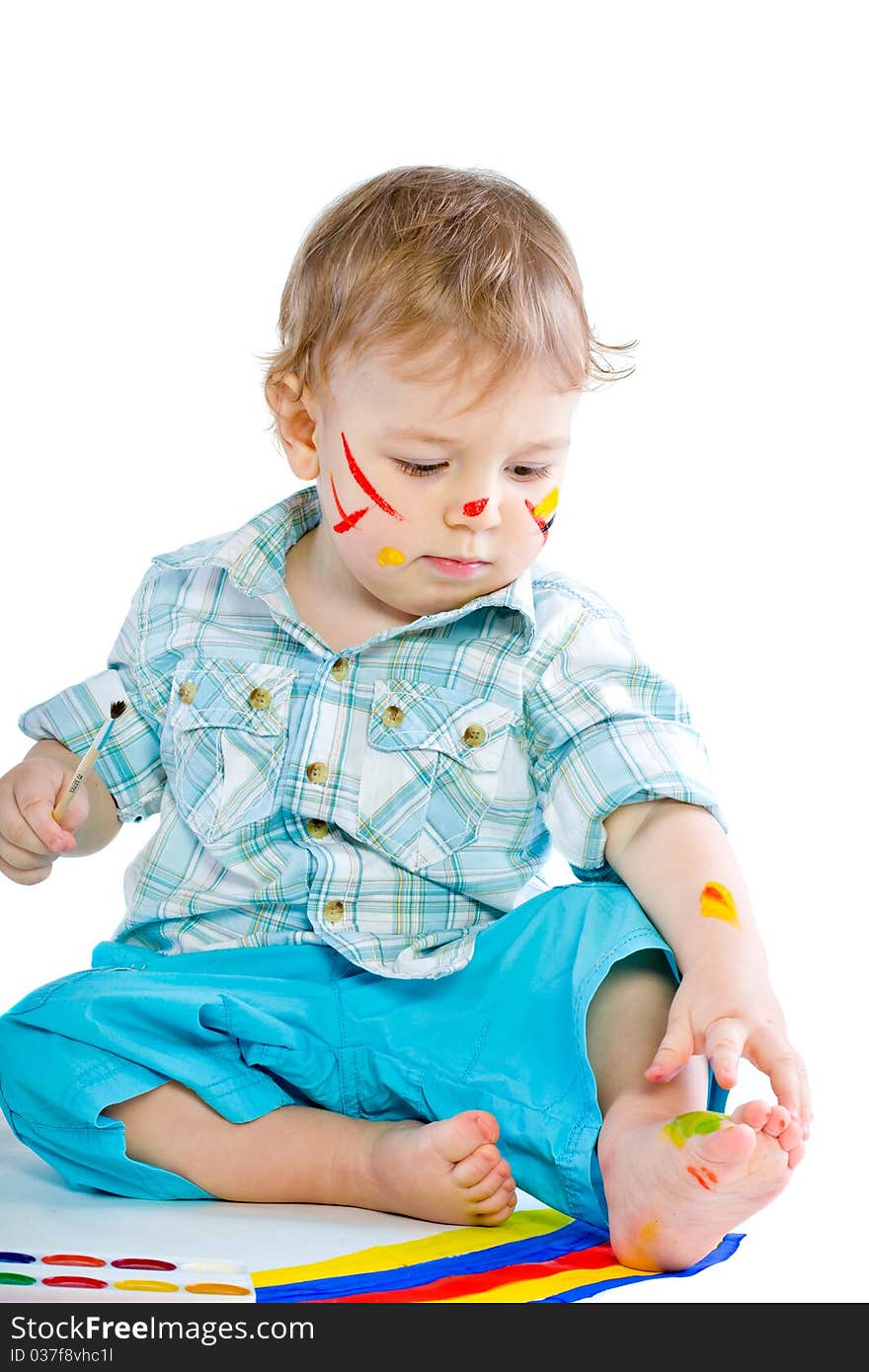 Beautiful baby covered in bright paint with paint brush. Isolated.