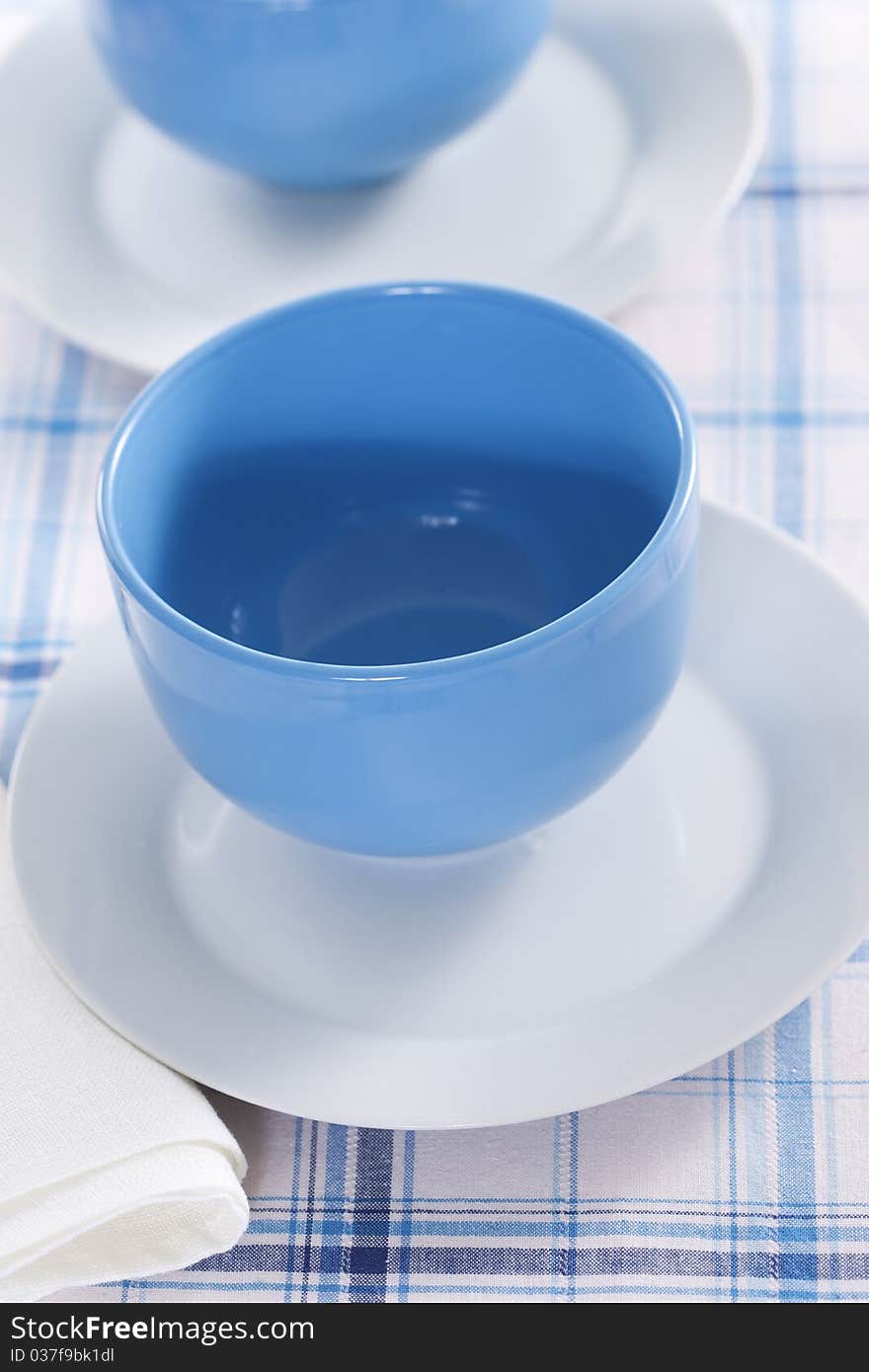 Two empty blue plates for the soup on a checkered tablecloth