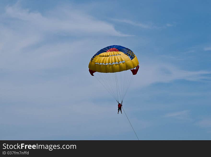 Paraglider launching from the ridge with colorful canopy against a blue sky. Paraglider launching from the ridge with colorful canopy against a blue sky.