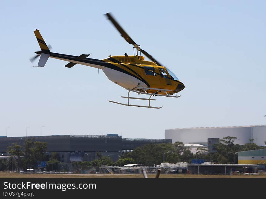 Yellow modern helicopter flying low overhead. Yellow modern helicopter flying low overhead.