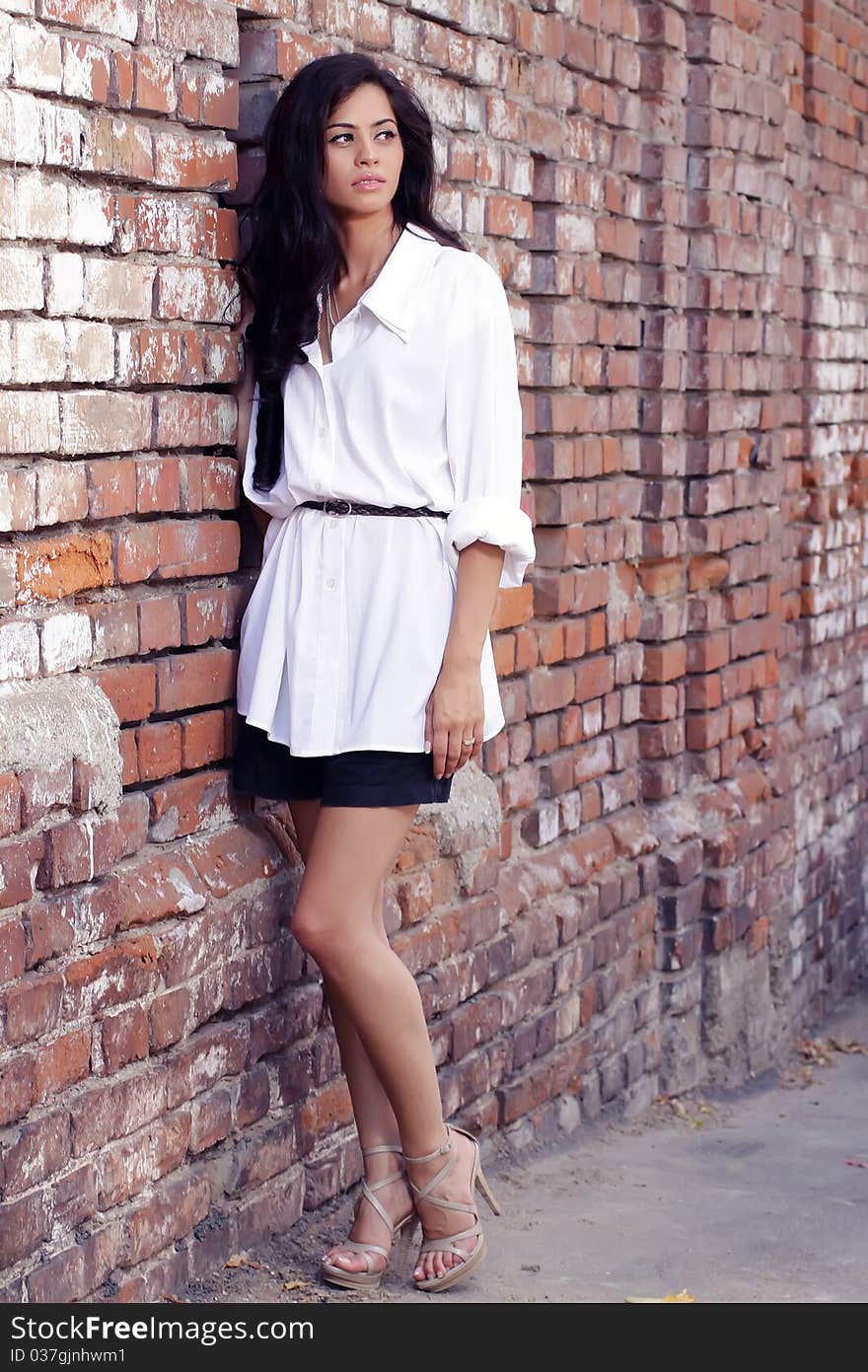 Cute brunette posing against a brick wall. Cute brunette posing against a brick wall