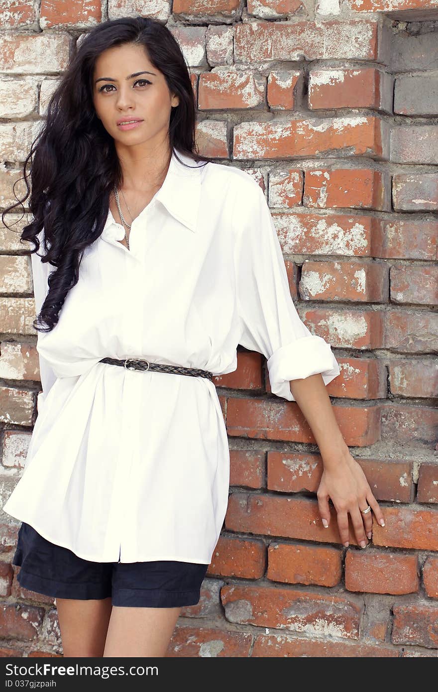 Cute brunette posing against a brick wall. Cute brunette posing against a brick wall