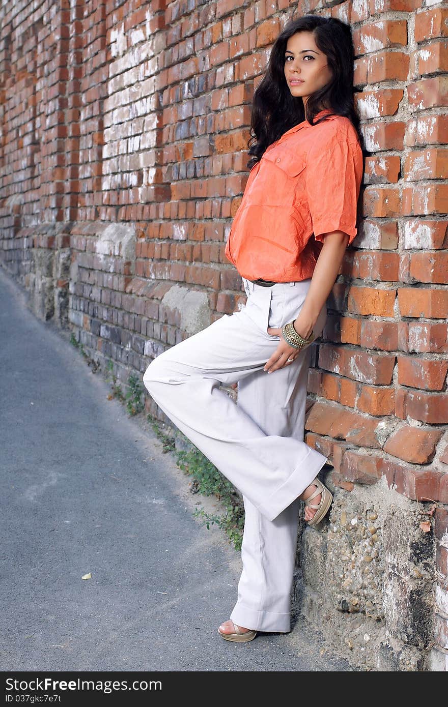 Cute brunette posing against a brick wall. Cute brunette posing against a brick wall