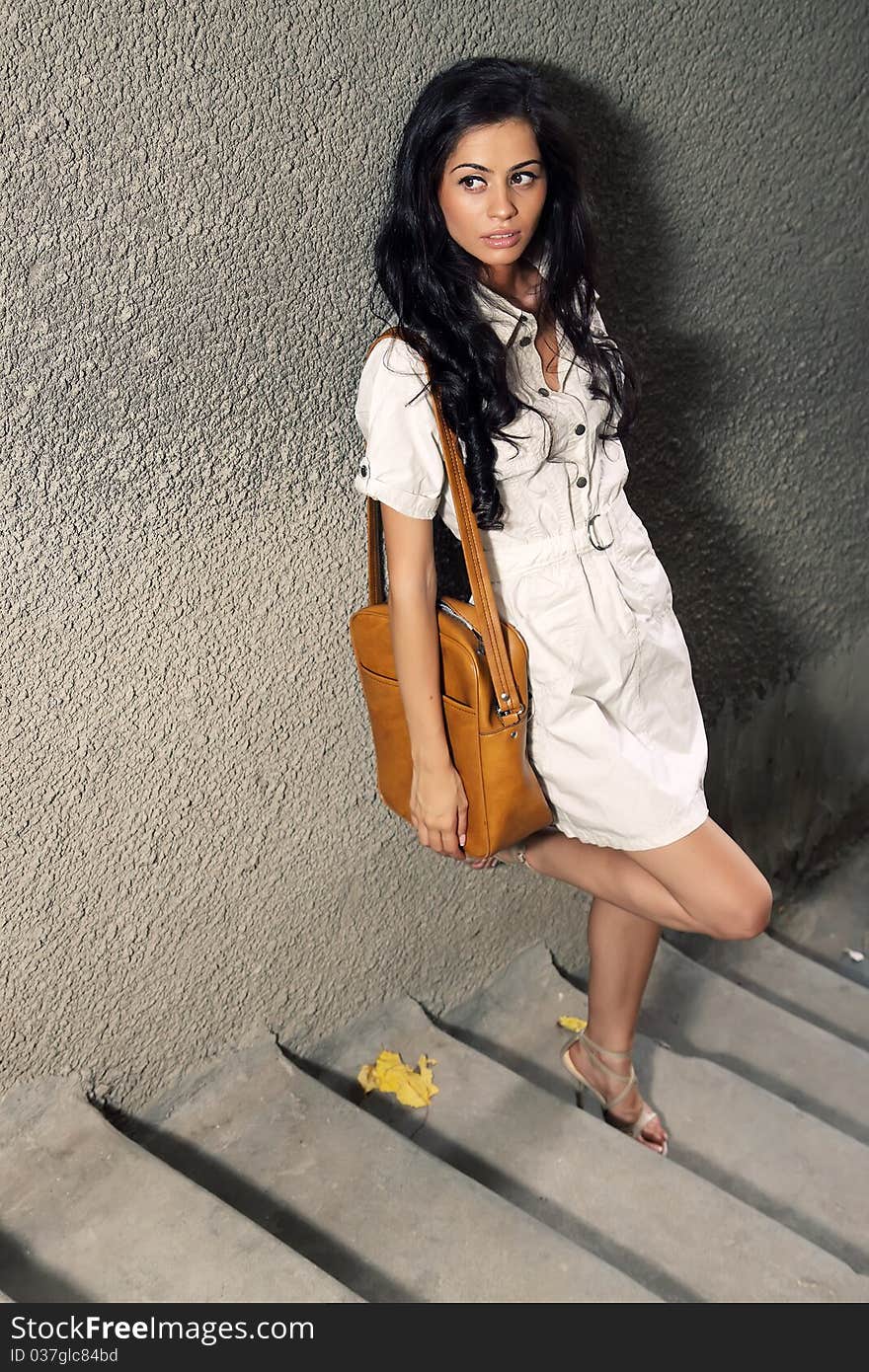 Beautiful girl in white dress and dark hair waiting on stairs