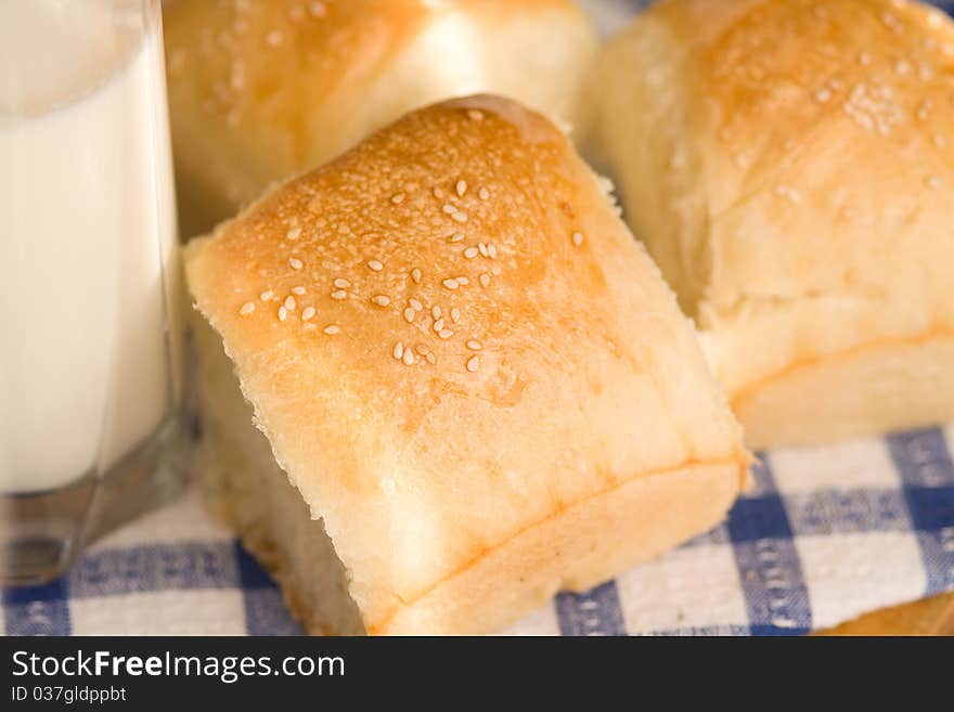 Homemade bread buns with sesame seeds and glass of milk