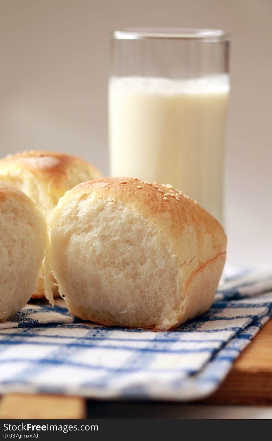 Homemade bread buns with sesame seeds and glass of milk