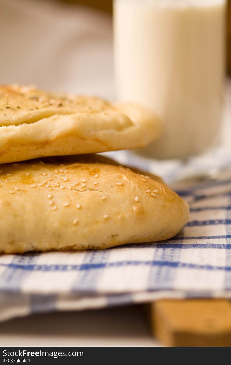 Homemade bread buns with sesame seeds and glass of milk