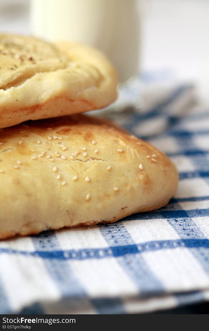 Homemade bread buns with sesame seeds and glass of milk