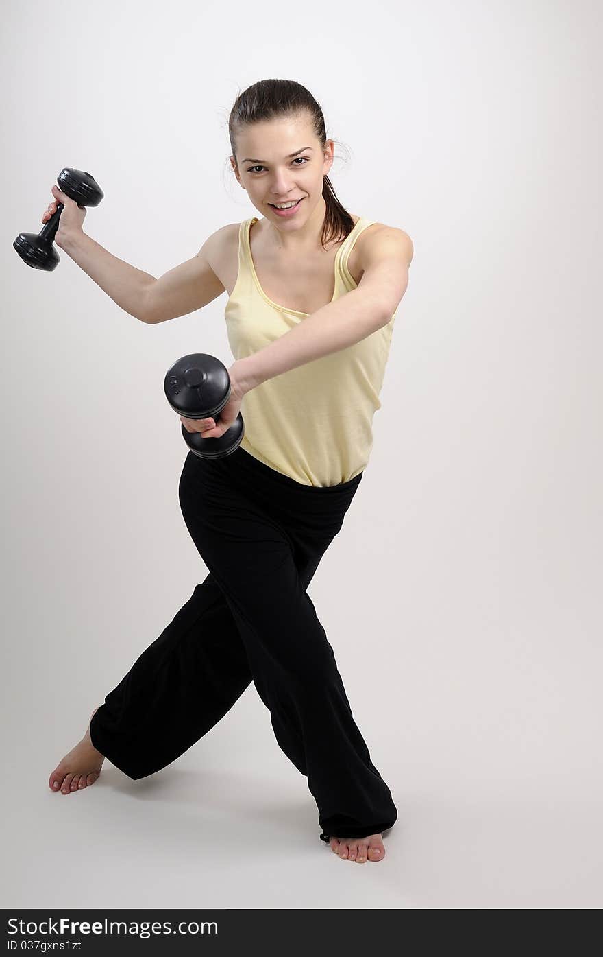 Young woman training her body and muscles with dumbbells. Young woman training her body and muscles with dumbbells