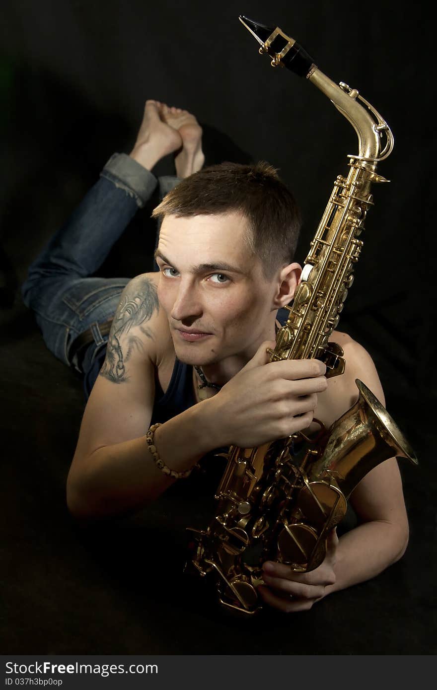 The young jazzman lie on the floor with saxophone. The young jazzman lie on the floor with saxophone