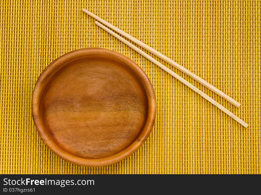 Empty Wooden Bowl with Chopsticks on bamboo mat